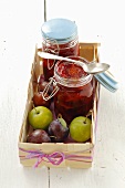 Plum jam and fresh plums in a wooden basket
