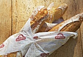 Baguettes wrapped in paper on a wooden surface