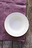 An empty plate on a purple cloth