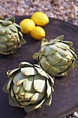 Artichokes and lemons on a black plate