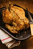 A whole roast chicken in a roasting tin