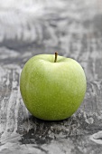 A Granny Smith apple on a wooden surface