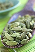 Cardamom pods on a wooden scoop