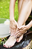 A woman giving herself a pedicure in a garden