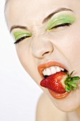 Young woman with a strawberry in her mouth