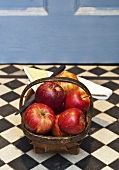 A basket of Royal Gala apples in front of a wooden door