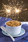An apple crumble with two sparklers