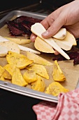 Sliced vegetables being placed on a baking tray