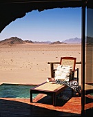 Liegestuhl auf Holzterrasse mit kleinem Pool & Fernblick auf wüstenartige Landschaft