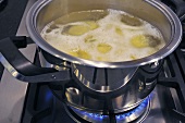 Boiling potatoes in a pan on a gas cooker
