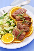 Sliced duck breast with orange slices, rosemary and couscous