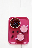 Two berry smoothies with a dish of fresh berries