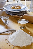 Flour, sugar, rolling pin and crockery on a table