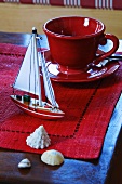 Red cup & saucer & maritime decorations on coffee table