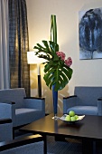 Wohnzimmer mit Sesseln, Couchtisch, Stehlampe & Philodendron in Bodenvase