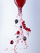 Wild berry juice and berries pouring out of bottle