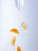 Water and orange wedges pouring out of bottle
