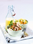 Prawn & noodle salad, fruit salad & orange juice on newspaper