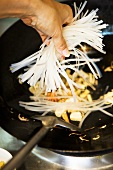 Putting rice noodles into wok (Thailand)