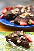 Piece of chocolate cake with cashew nuts and strawberries