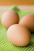 Drei braune Eier auf grünem Tuch