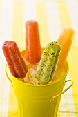 Assorted fruit ice lollies in a yellow bucket