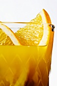 Orange juice with orange slices in glass (close-up)