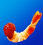Prawn tail with cocktail sauce against blue background