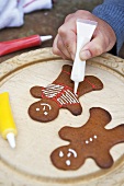 Decorating gingerbread men with writing icing