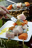 Brushing fish kebabs with herb oil