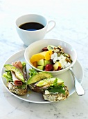 Open sandwiches with avocado, fruit salad with soft cheese, cup of coffee