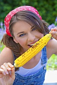 Young woman eating grilled corn on the cob