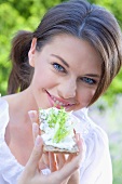 Junge Frau isst Knäckebrot mit Hüttenkäse und Gurke