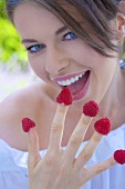 Young woman with raspberries on her fingers