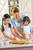 Mother and two daughters kneading pizza dough
