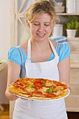 Frau hält frisch gebackene Pizza