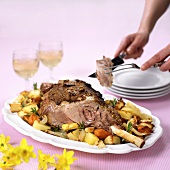Carving leg of lamb on roasted vegetables