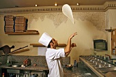 Italian pizza baker throwing dough into the air