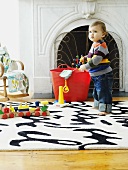Toddler with toys on rug in front of fireplace