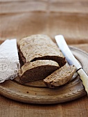 Partly-sliced loaf of bread on breadboard