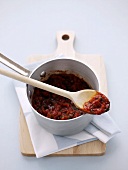 Tomato sauce in pan and on wooden spoon