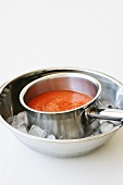 Gazpacho im Kochtopf in Schüssel mit Eiswürfeln abkühlen