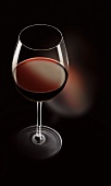 A glass of red wine against a black background