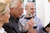 Eine Frau und zwei Männer testen den Rotwein