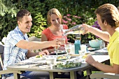 Junge Leute mit Vorspeisen und Getränken am Tisch im Freien