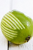 A lime with strips of zest removed