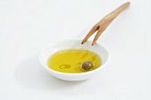 Olive oil with olive in a small dish