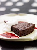 A piece of chocolate cake with cream and raspberry sauce