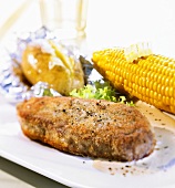 Breaded beef steak with corn on the cob and baked potato