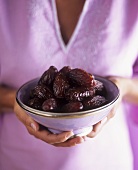 Hands holding a dish of dates
